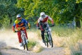 Two Fully Equipped Professional Downhill Cyclists Riding Bikes on the Summer Trail Royalty Free Stock Photo