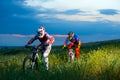 Two Fully Equipped Professional Downhill Cyclists Riding Bikes on the Summer Trail Royalty Free Stock Photo