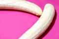 Two fully peeled bananas on a bright pink background top view close-up. Flat lay with copy space for text Royalty Free Stock Photo