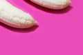 Two fully peeled bananas on a pink background top view close-up. Flat lay with copy space for text Royalty Free Stock Photo