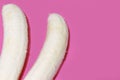 Two fully peeled bananas on a pink background top view. Flat lay with copy space for text Royalty Free Stock Photo