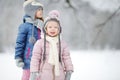 Two funny adorable little sisters having fun together in beautiful winter park during snowfall Royalty Free Stock Photo