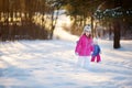 Two funny adorable little sisters having fun together in beautiful winter park Royalty Free Stock Photo