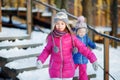 Two funny adorable little sisters having fun together in beautiful winter park Royalty Free Stock Photo