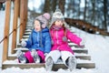 Two funny adorable little sisters having fun together in winter park Royalty Free Stock Photo