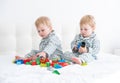 Two funny boys brothers twins on white bed in pajamas playing in constructor