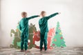 Two funny boys in a Santa Claus hat are playing with horses drawn on cardboard. The guys have fun at home. Christmas holiday conce