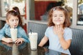 Two funny Caucasian little preschool sisters siblings eat dessert play in cafe. Royalty Free Stock Photo