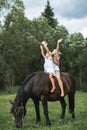 Two funny children girls sisters friends riding a horse together through a field. Girls sitting on a horse and holding Royalty Free Stock Photo
