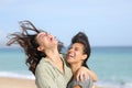 Two funny friends laughing hilariously on the beach Royalty Free Stock Photo