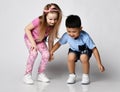 Two funny frolic kids friends boy and girl in summer clothes stand together looking down, noticed something on floor