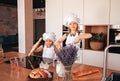 Two funny girls in the kitchen wearing a chef`s hat and white apron playing in the kitchen Royalty Free Stock Photo