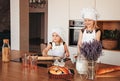 Two funny girls in the kitchen wearing a chef`s hat and white apron playing in the kitchen Royalty Free Stock Photo