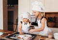 Two funny girls in the kitchen wearing a chef`s hat and white apron playing in the kitchen Royalty Free Stock Photo