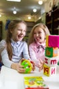 Two funny girls playing with alphabet blocks in the library Royalty Free Stock Photo