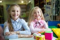 Two funny girls playing with alphabet blocks in library Royalty Free Stock Photo