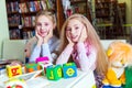 Two funny girls playing with alphabet blocks in library Royalty Free Stock Photo