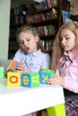 Two funny girls playing with alphabet blocks in library Royalty Free Stock Photo