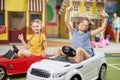 Two funny girls playing with electric toy car. Royalty Free Stock Photo