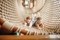 Two girls poses in rope net, children game center
