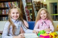 Two funny girls are reading books in the library. Wooden alphabet blocks Royalty Free Stock Photo