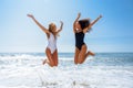 Two funny girls in swimsuit jumping on a tropical beach Royalty Free Stock Photo