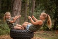 two funny girls swing on a swing