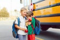 Two funny happy Caucasian boys friends students kids with apples hugging near yellow bus on 1 September Royalty Free Stock Photo