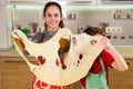 Two funny kids with thin dough sheet, making the pizza