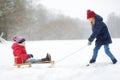 Two funny little girls having fun with a sleigh in beautiful winter park. Cute children playing in a snow. Royalty Free Stock Photo