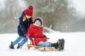Two funny little girls having fun with a sleigh in beautiful winter park. Cute children playing in a snow. Royalty Free Stock Photo