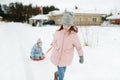 Two funny little girls having fun with a sleigh in beautiful winter park. Cute children playing in a snow Royalty Free Stock Photo