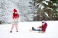 Two funny little girls having fun with a sleight in beautiful winter park. Cute children playing in a snow. Royalty Free Stock Photo