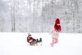 Two funny little girls having fun with a sleight in beautiful winter park. Cute children playing in a snow. Royalty Free Stock Photo