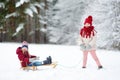 Two funny little girls having fun with a sleight in beautiful winter park. Cute children playing in a snow. Royalty Free Stock Photo