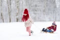 Two funny little girls having fun with a sleight in beautiful winter park. Cute children playing in a snow. Royalty Free Stock Photo