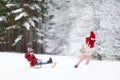 Two funny little girls having fun with a sleight in beautiful winter park. Cute children playing in a snow. Royalty Free Stock Photo