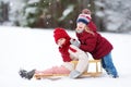 Two funny little girls having fun with a sleight in beautiful winter park. Cute children playing in a snow. Royalty Free Stock Photo