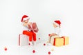 Two funny little kids in Santa hat sitting on gift boxes. Isolated on white background. Christmas and new year concept Royalty Free Stock Photo