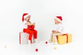 Two funny little kids in Santa hat sitting on gift boxes. Isolated on white background. Christmas and new year concept Royalty Free Stock Photo