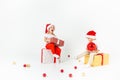 Two funny little kids in Santa hat sitting on gift boxes. Isolated on white background. Christmas and new year concept