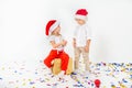 Two funny little kids in Santa hat sitting on gift boxes. Isolated on white background. Christmas and new year concept Royalty Free Stock Photo