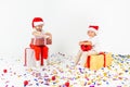 Two funny little kids in Santa hat sitting on gift boxes. Isolated on white background, confetti on a floor. Christmas and new Royalty Free Stock Photo