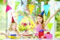 Two funny little sisters having birthday party at home, blowing candles on birthday cake Royalty Free Stock Photo