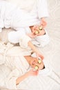 Two funny young women with cucumbers on eyes and towel on their heads lying on the bed Royalty Free Stock Photo