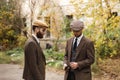 Two gangsters in suits stand on the street and look at the gun. Retro. Outdoors.