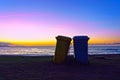 Two garbage cans on beach at sunset