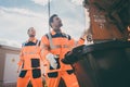 Two garbagemen working together on emptying dustbins