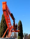 Two gardeners prunes the cypress trees in a park from an aerial platform.