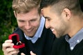 Engagement proposal betwen two gay men as one man proposes with an engagement ring in red box Royalty Free Stock Photo